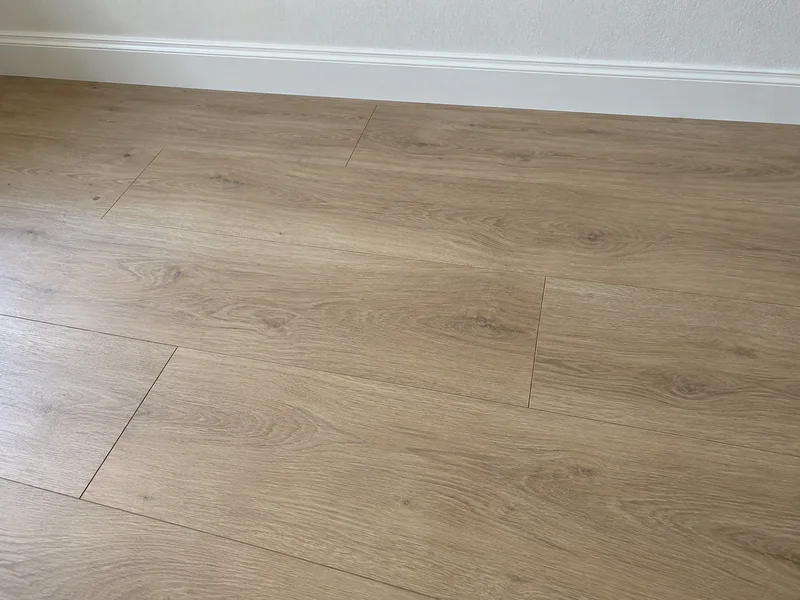 Light oak-look laminate boards meeting a white baseboard