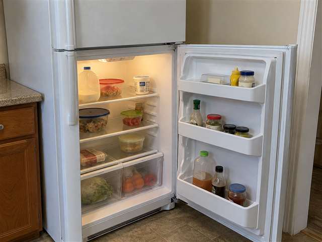 White refrigerator with its main door open, showing shelves and door bins